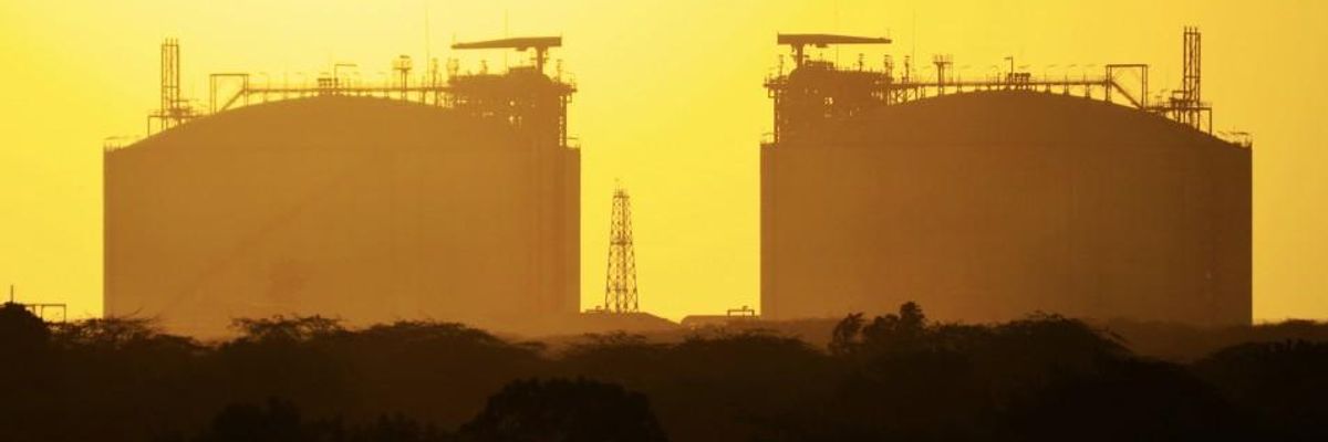 The sun sets behind liquified natural gas tanks in Hazira, Gujarat, India.