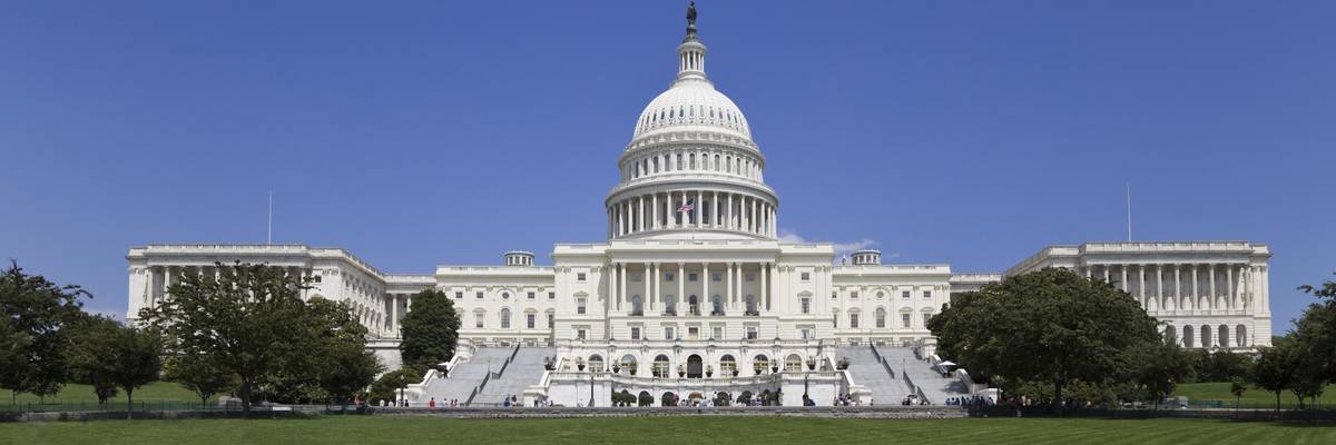 The U.S. Capitol Building with a green lawn in front and a blue sky above.