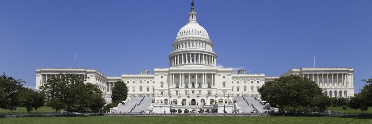 The U.S. Capitol Building with a green lawn in front and a blue sky above.