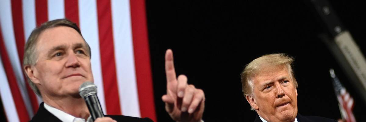 Then-Sen. David Perdue (R-Ga.) gestures as he speaks next to President Donald Trump during a rally to support Republican Senate candidates at Valdosta Regional Airport in Valdosta, Georgia on December 5, 2020.