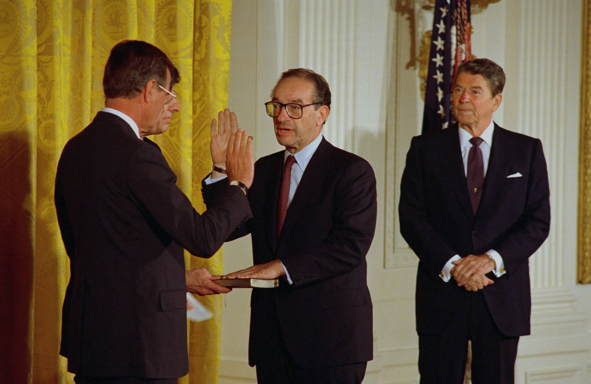 Then-Vice President George H. W. Bush swears in Alan Greenspan while President Ronald Reagan looks on.