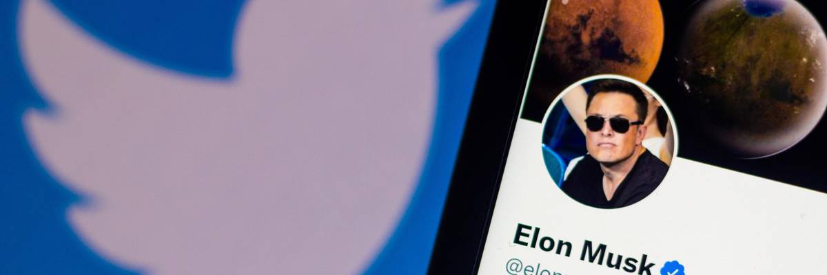 This photo illustration shows the Twitter logo behind a smartphone with Elon Musk's official profile on April 11, 2022.