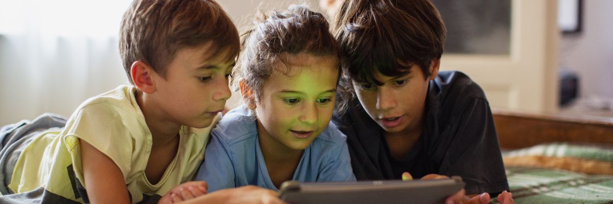 three children use a tablet
