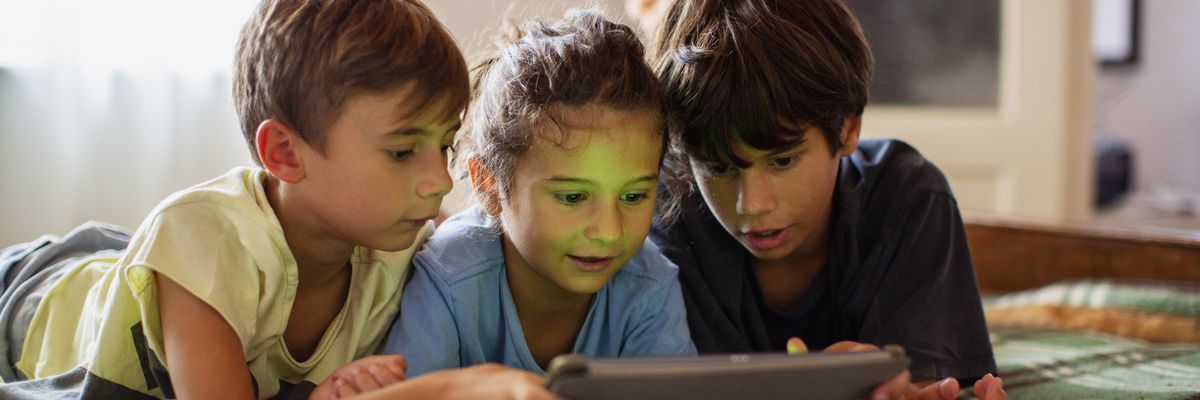 three children use a tablet
