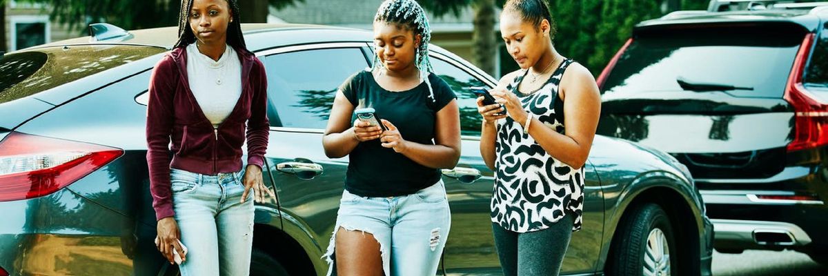 Three girls hold cell phones.