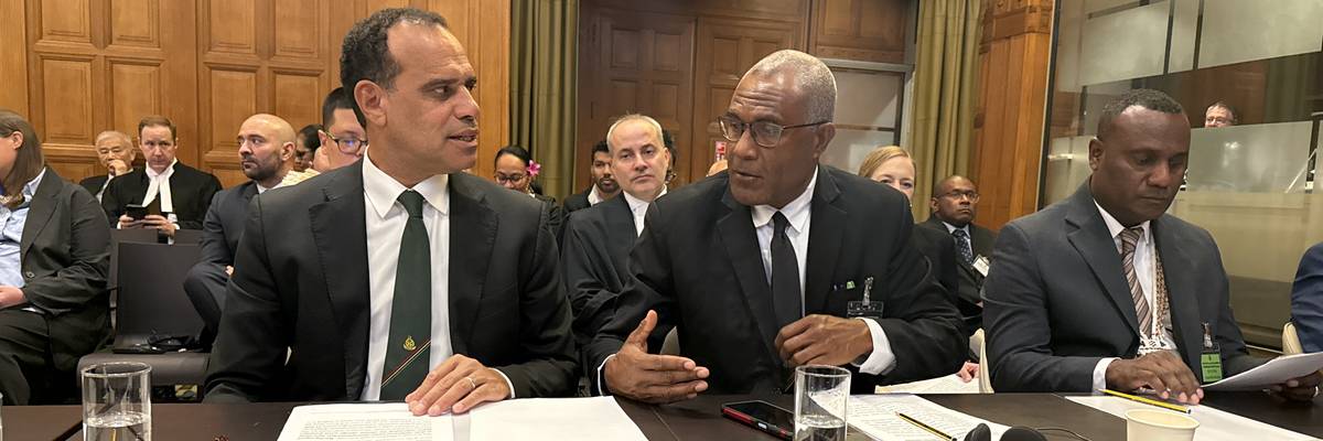 Three men in suits sit at a table.