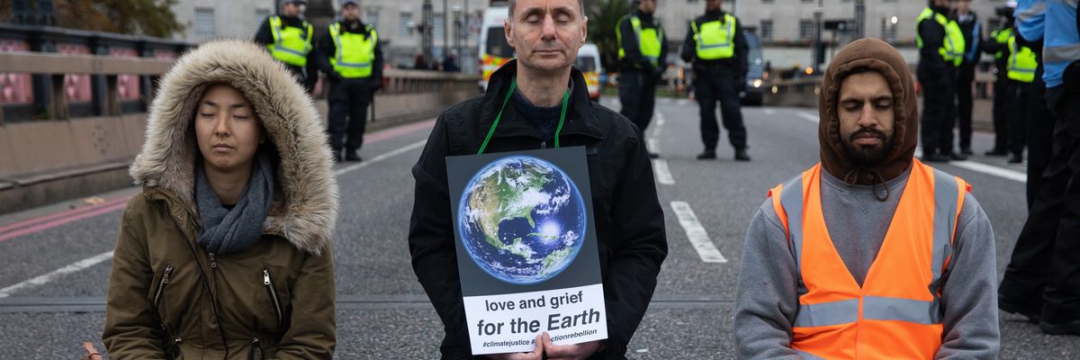 Three people kneel on pavement.