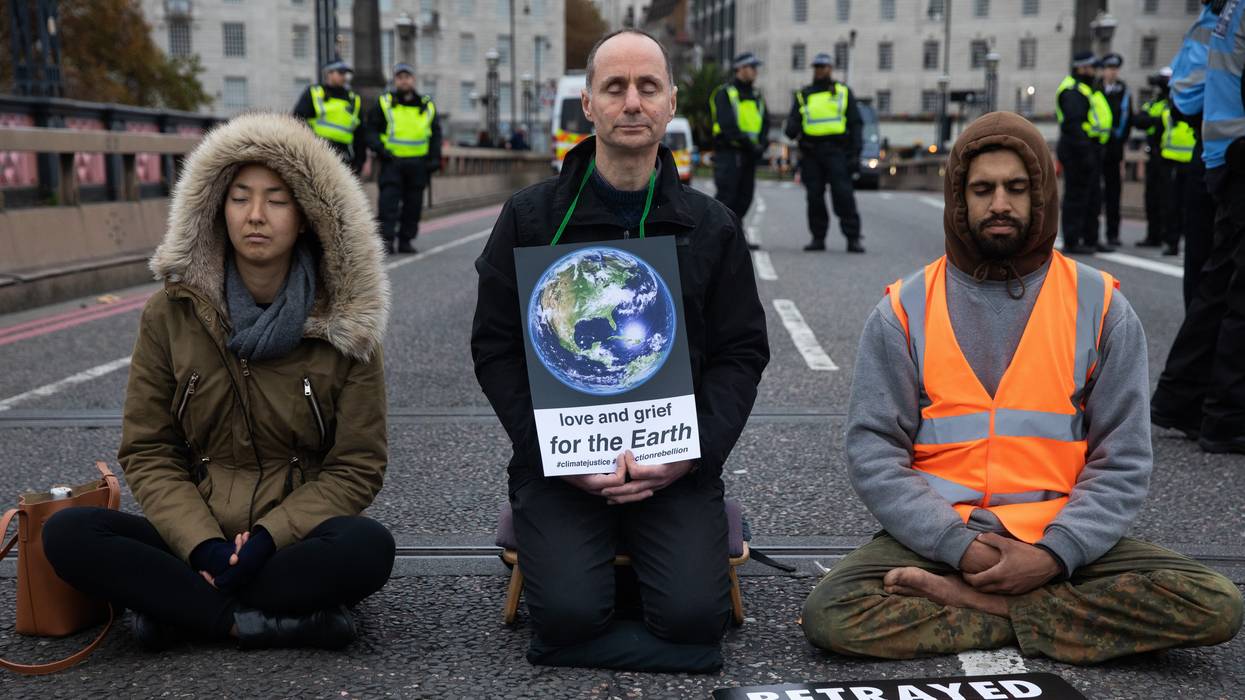 Three people kneel on pavement.