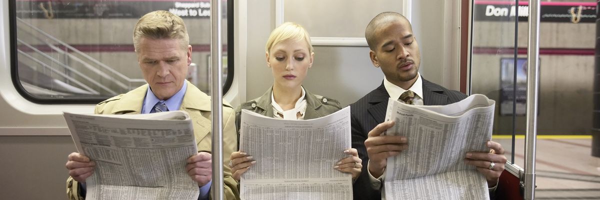 Three people on a subway train read newspapers.