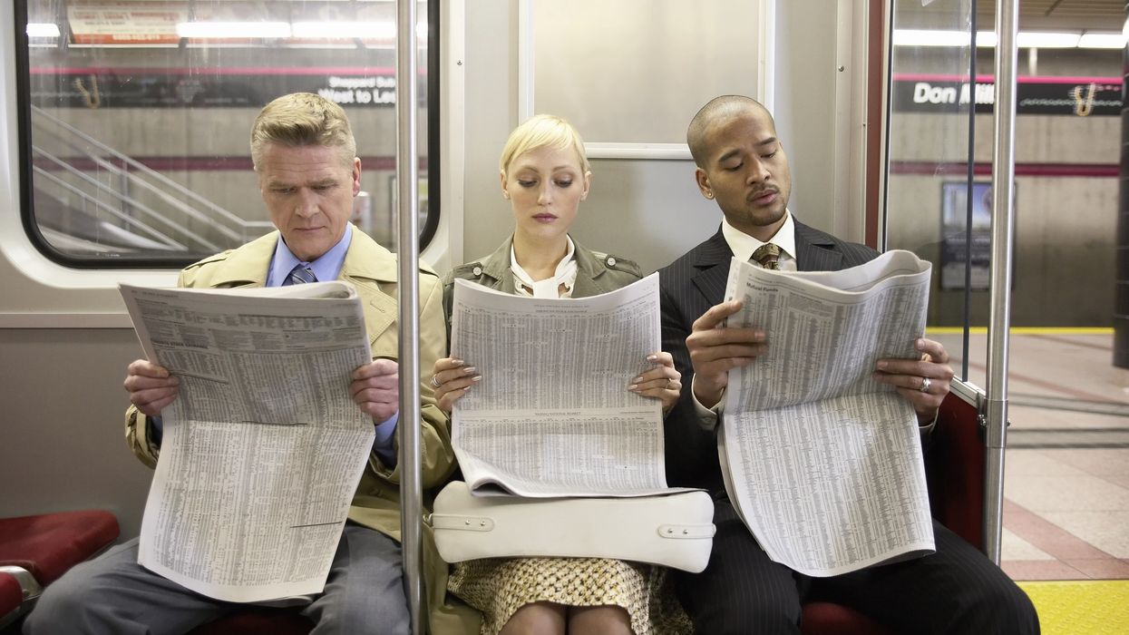 Three people on a subway train read newspapers.