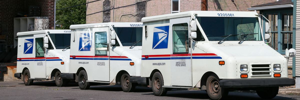 Three United States Postal Service (USPS) mail trucks.