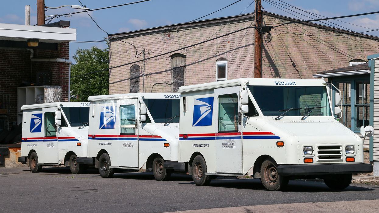 Three United States Postal Service (USPS) mail trucks.
