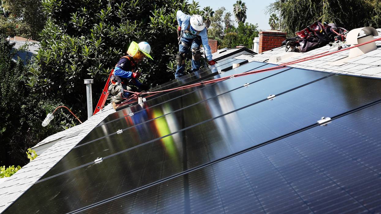 Tony Chang (L) and Sal Miranda install no-cost solar panels