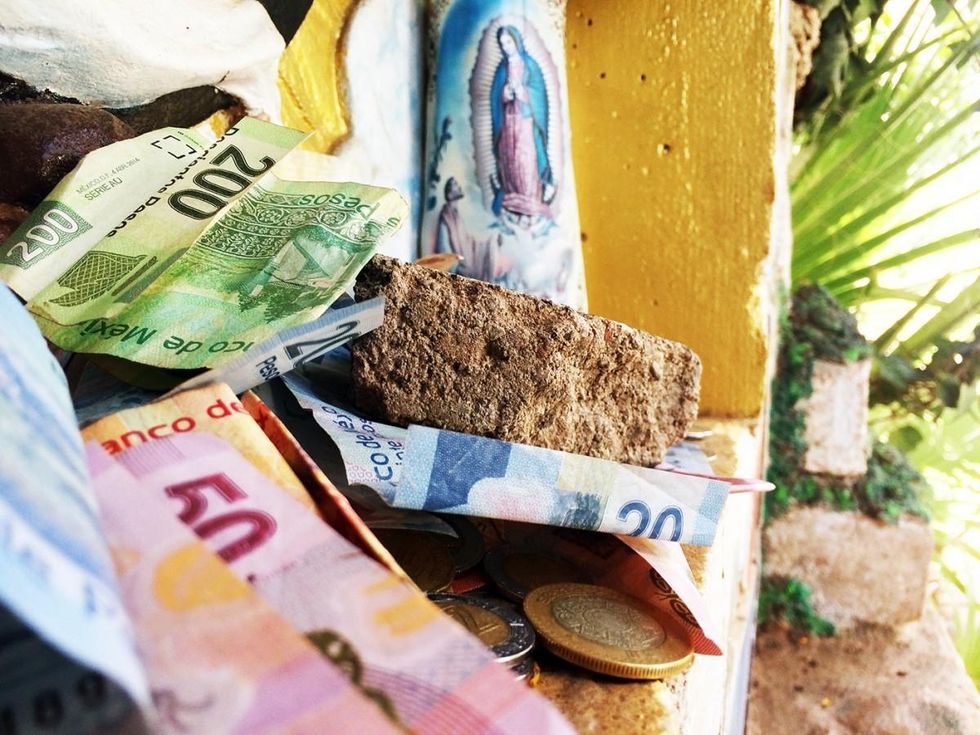 Top, framed in ivy, the altar of the Virgin Mary is one of many contemplative spots on the monastery grounds. Above, many asylum-seekers leave coins and bills at the altar. (Photo: Rose Lambert-Sluder)