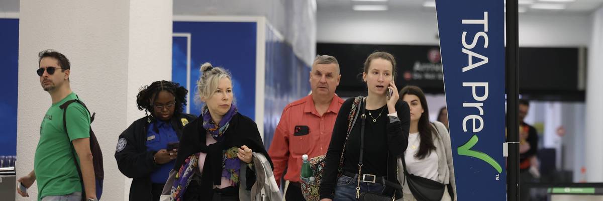 Travelers walk past a Transportation Security Administration PreCheck