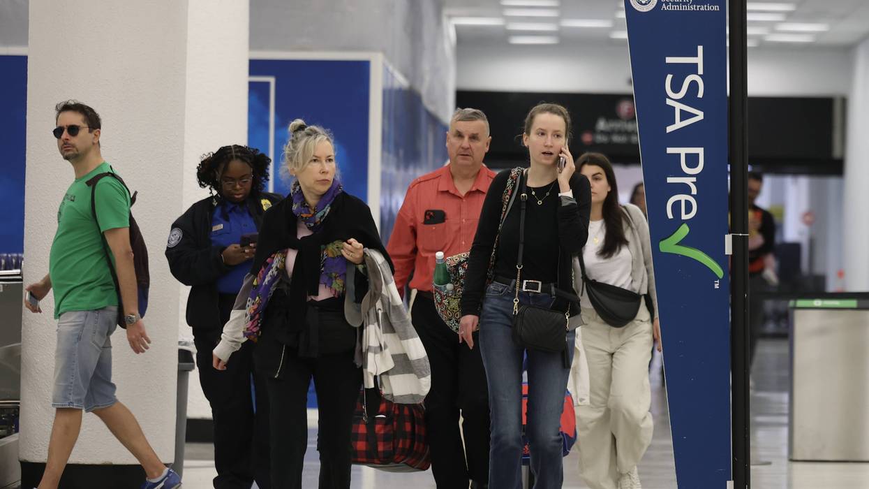 Travelers walk past a Transportation Security Administration PreCheck