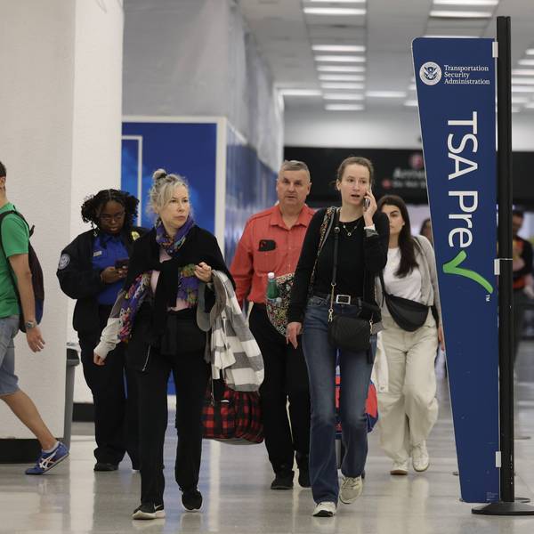 Travelers walk past a Transportation Security Administration PreCheck