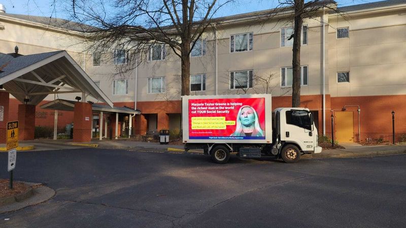 Truck protesting Marjorie Taylor Greene for threatening benefits.