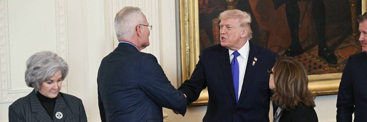 Trump and Darren Woods shake hands.