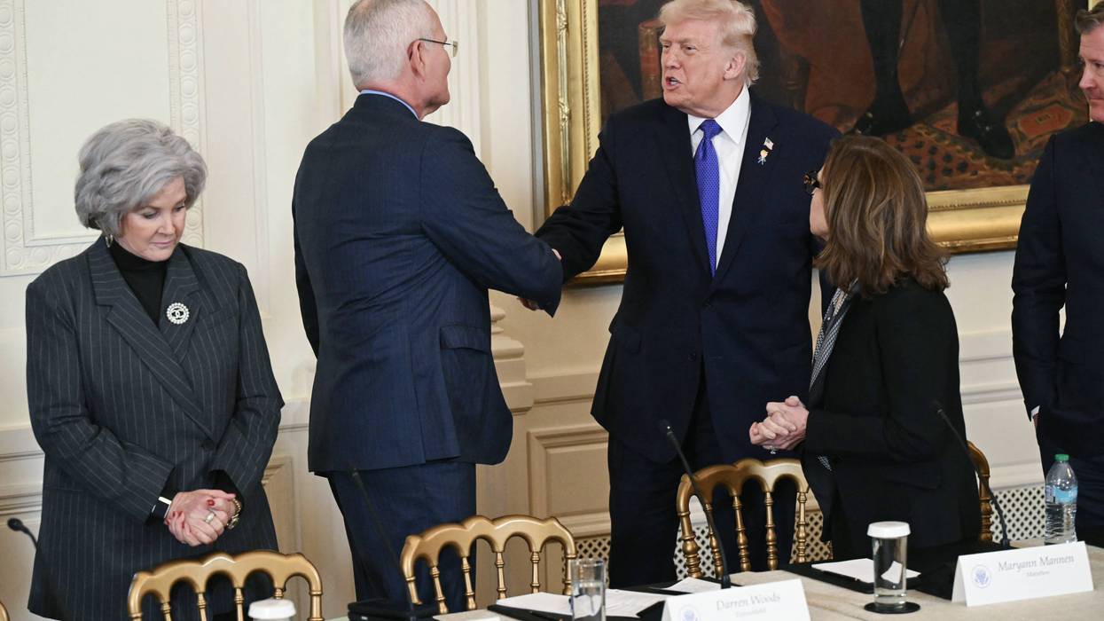 Trump and Darren Woods shake hands.