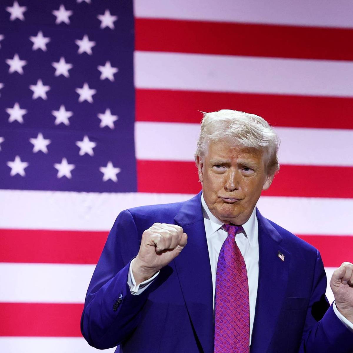 Trump dances in front of a giant US flag screen