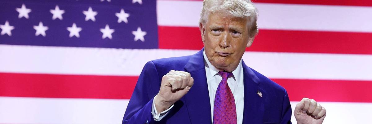 Trump dances in front of a giant US flag screen