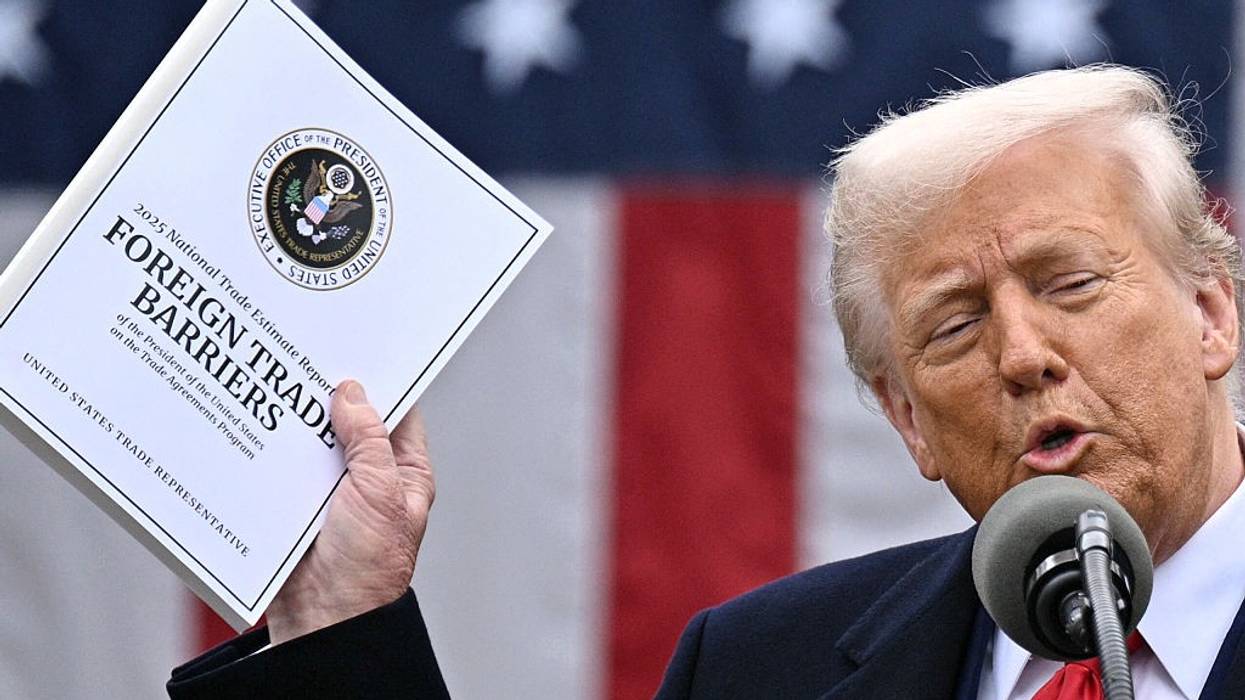 Trump holds a document while discussing tariffs.