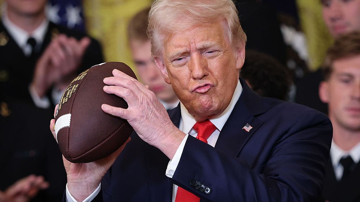 Trump holds an American football.