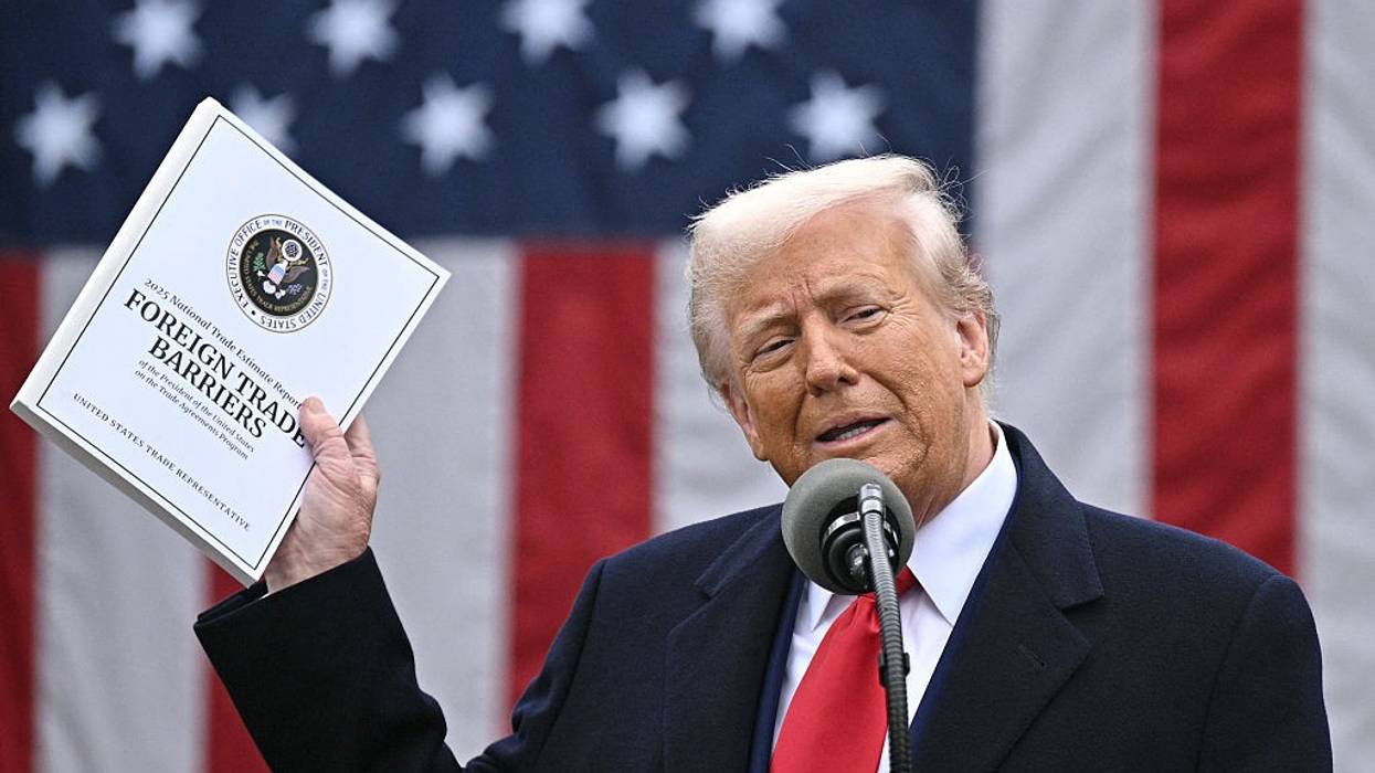 Trump holds up a paper while speaking about tariffs.