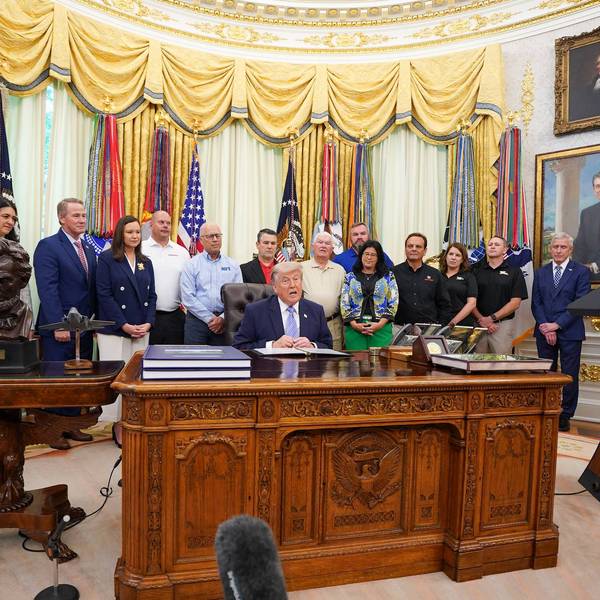 Trump speaks at the Oval Office surrounded by staff and supporters