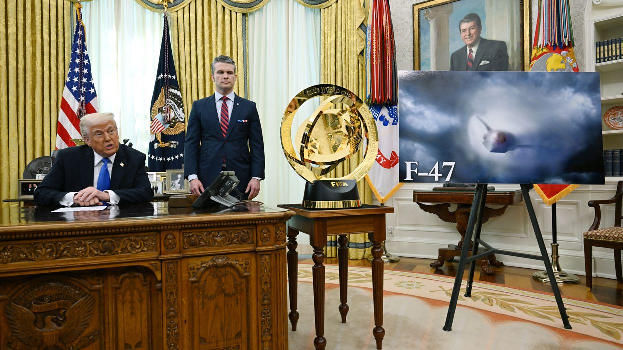 Trump speaks from desk next to image of F-47 fighter plane.