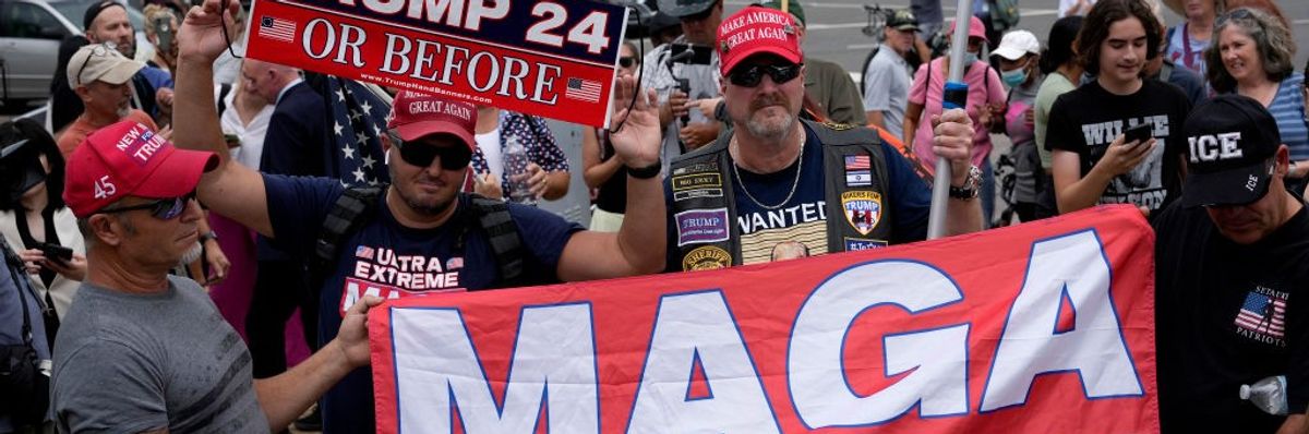 Trump supporters with signs and a banner reading MAGA.