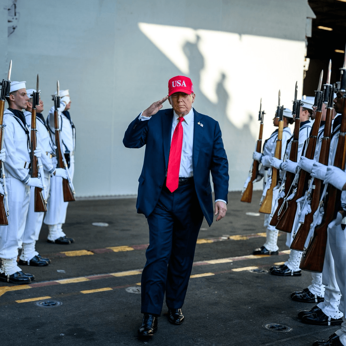 Trump walks through two rows of US sailors while saluting