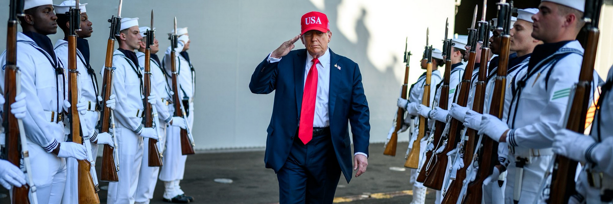 Trump walks through two rows of US sailors while saluting