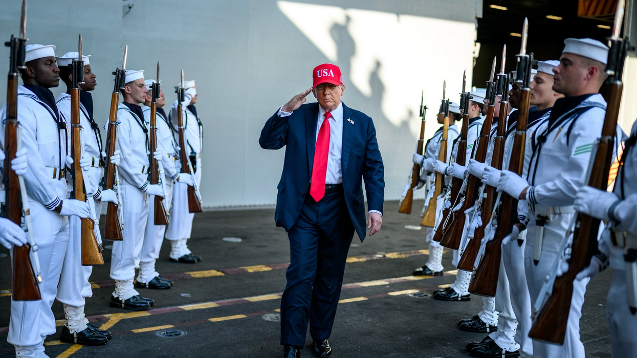 Trump walks through two rows of US sailors while saluting