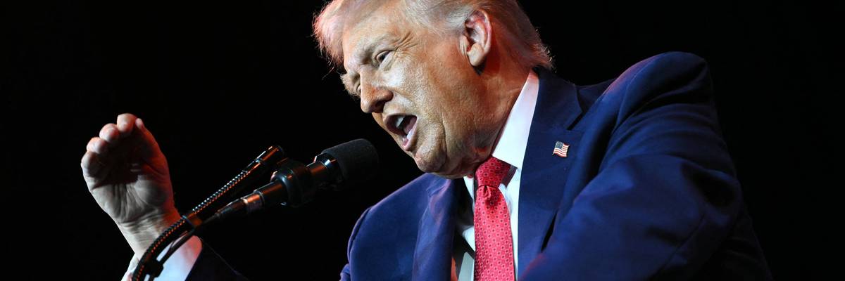 Trump yells into a microphone.