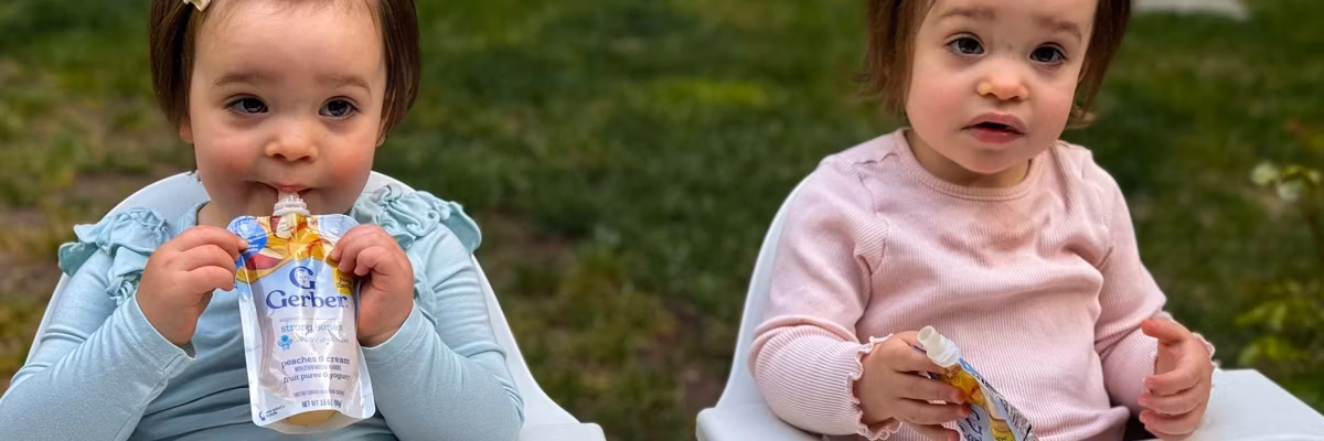 twin babies eat food from plastic pouches