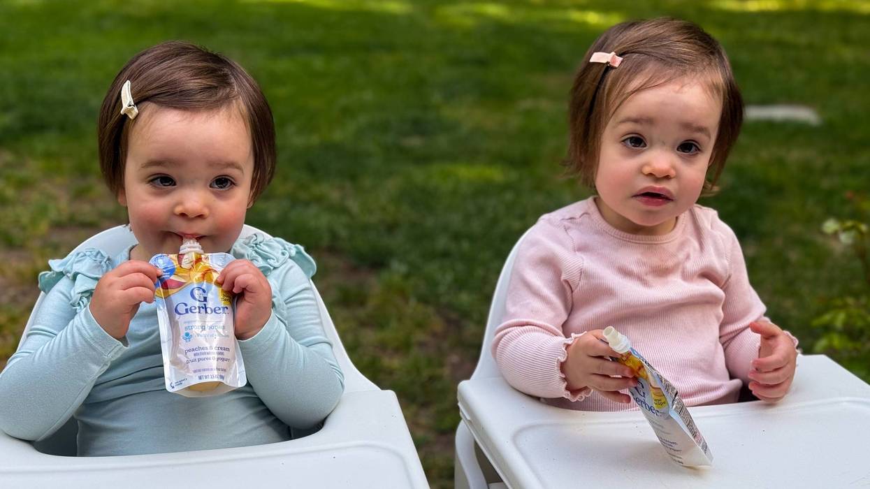twin babies eat food from plastic pouches