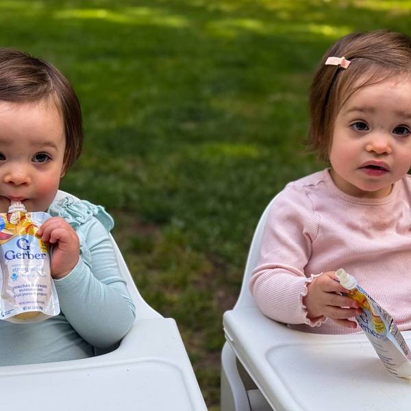 twin babies eat food from plastic pouches