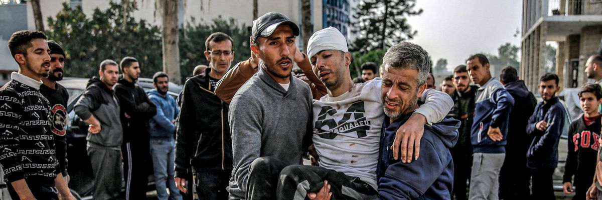 Two men carry an injured man