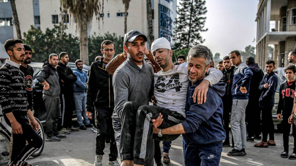 Two men carry an injured man