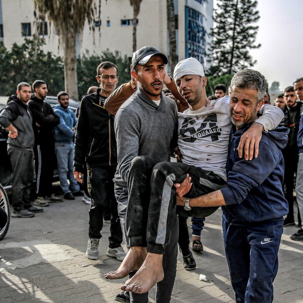 Two men carry an injured man