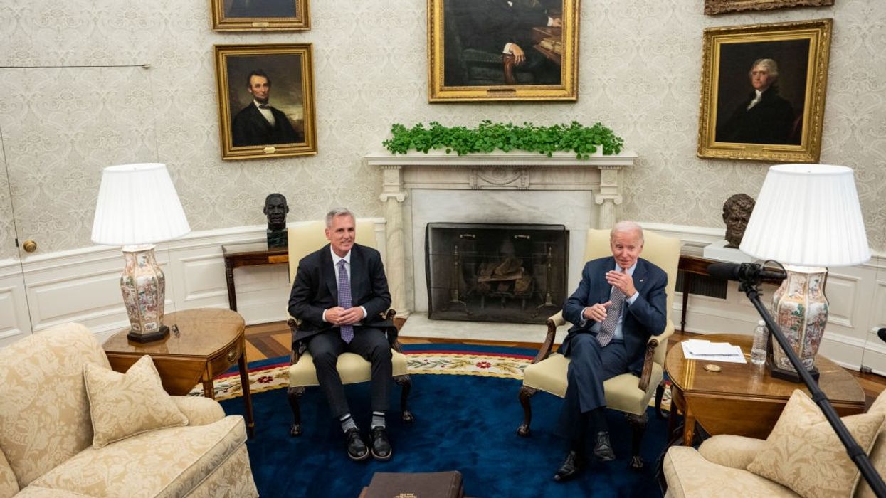 Two men in suits sit in chairs.