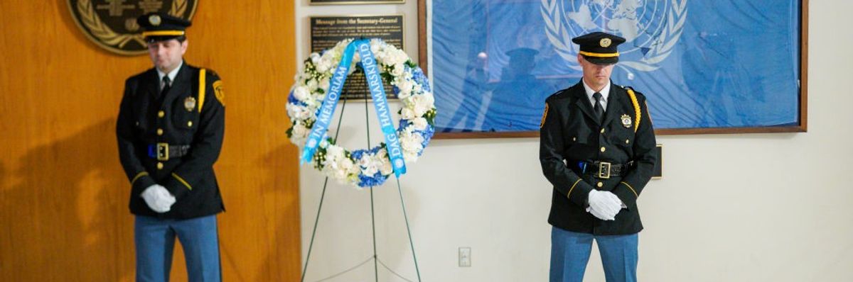 Two military guards stand on either side of a wreath for the International Day of Peace.