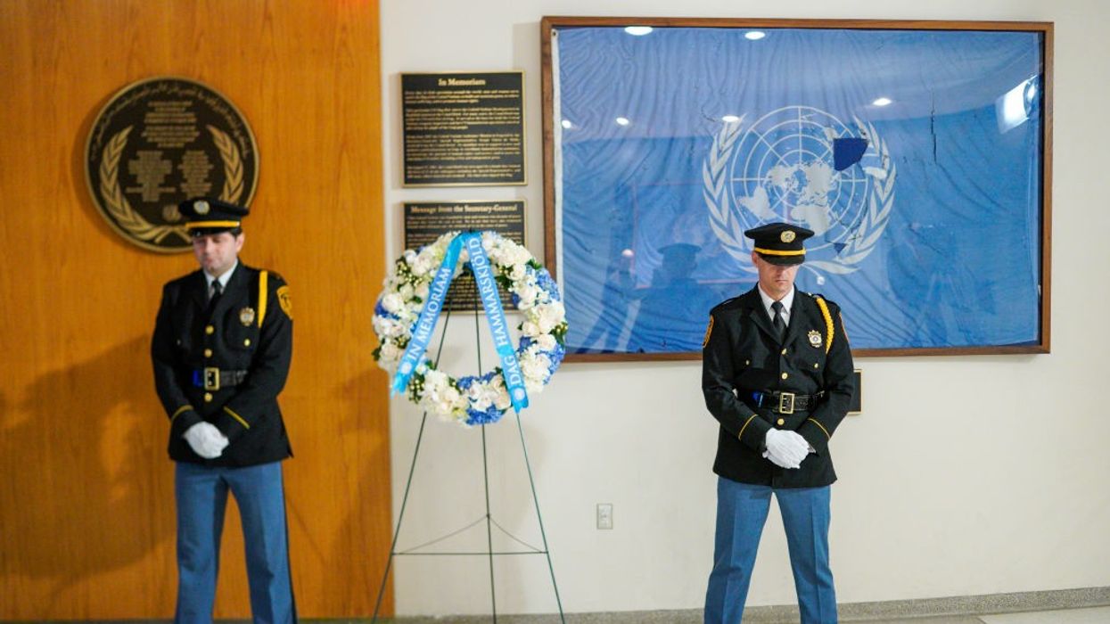 Two military guards stand on either side of a wreath for the International Day of Peace.