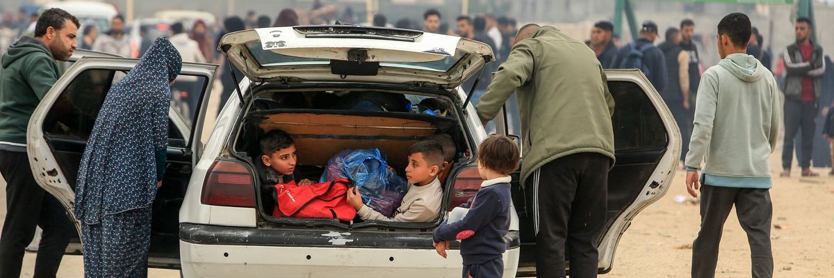 Two Palestinian children sit in the trunk of a car in a crowd migrating south to Rafah.