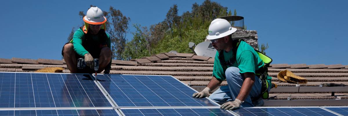 Two workers install solar panels on a home in Oak View, California on August 23, 2011.