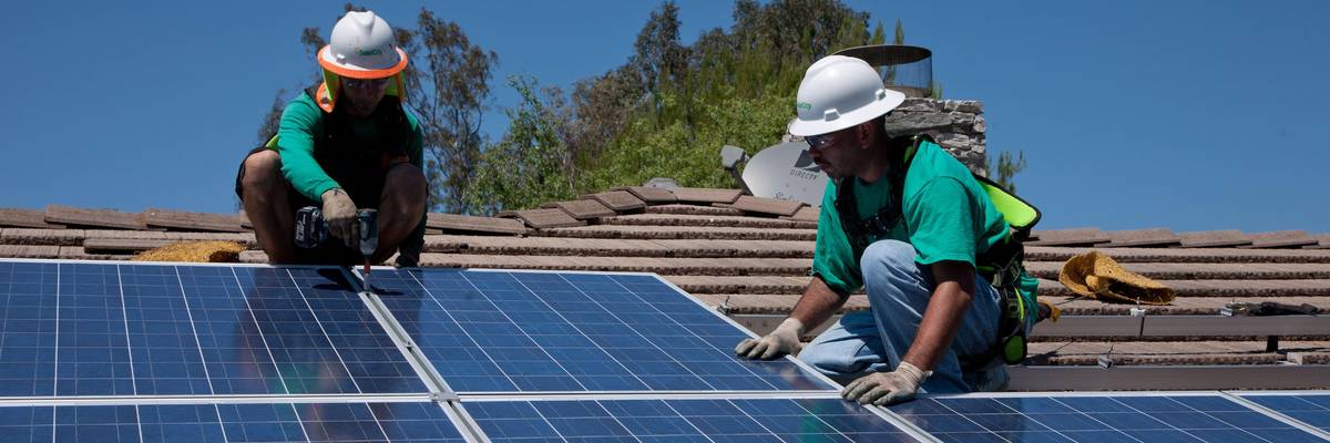 Two workers install solar panels on a home in Oak View, California on August 23, 2011.