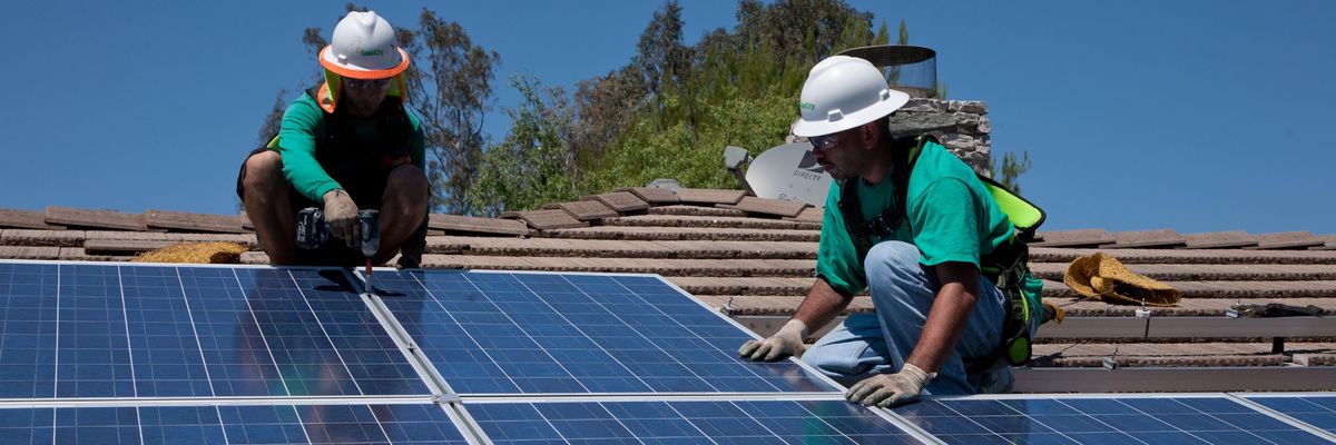 Two workers install solar panels on a home in Oak View, California on August 23, 2011.