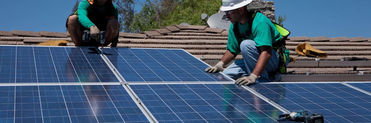 Two workers install solar panels on a home in Oak View, California on August 23, 2011.